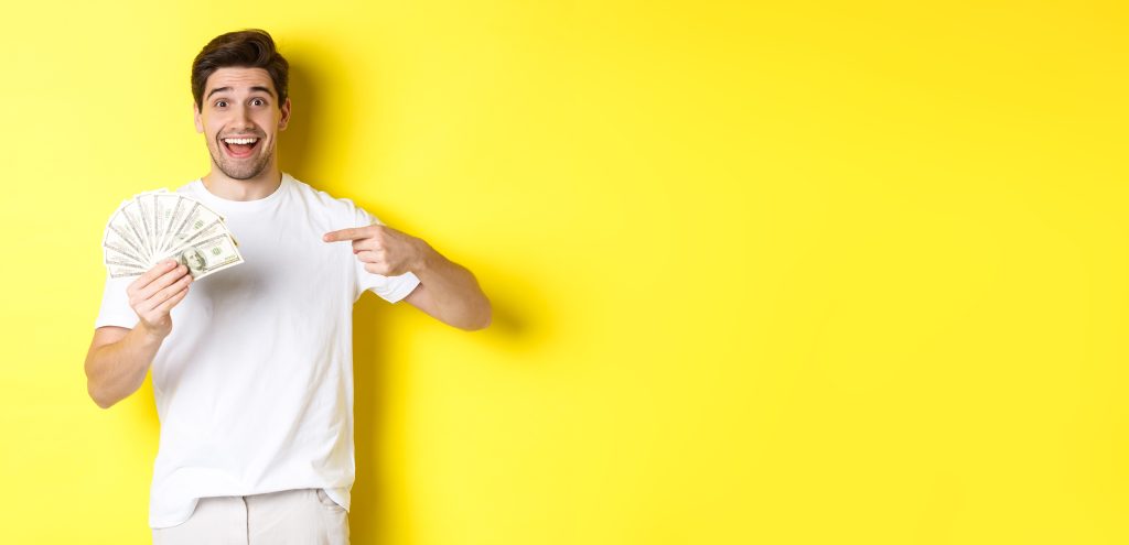 Happy Handsome Guy Pointing Finger Money Concept Credit Loan Standing Yellow Backgrou Scaled
